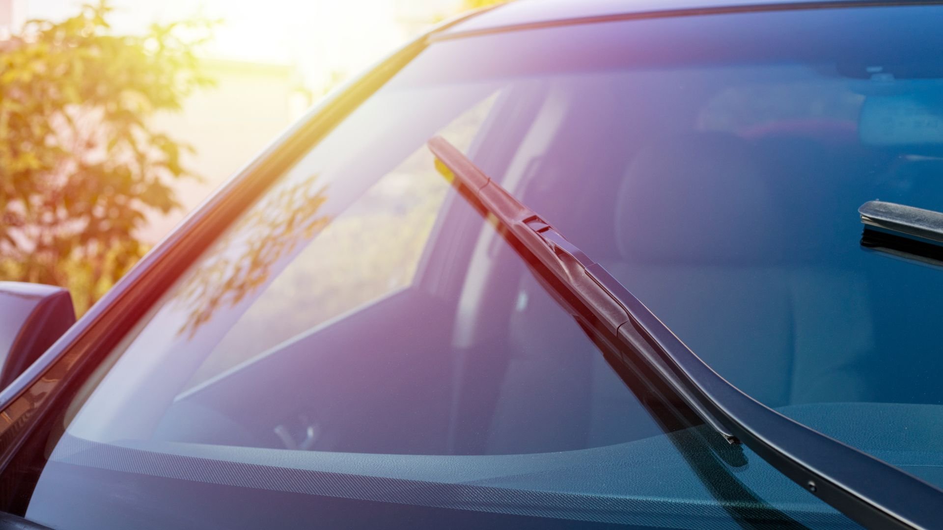Sunlight reflecting on car windshield with wipers in soft focus