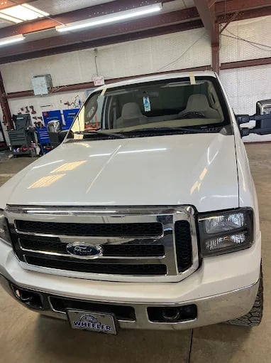 White Ford truck parked inside an automotive repair shop